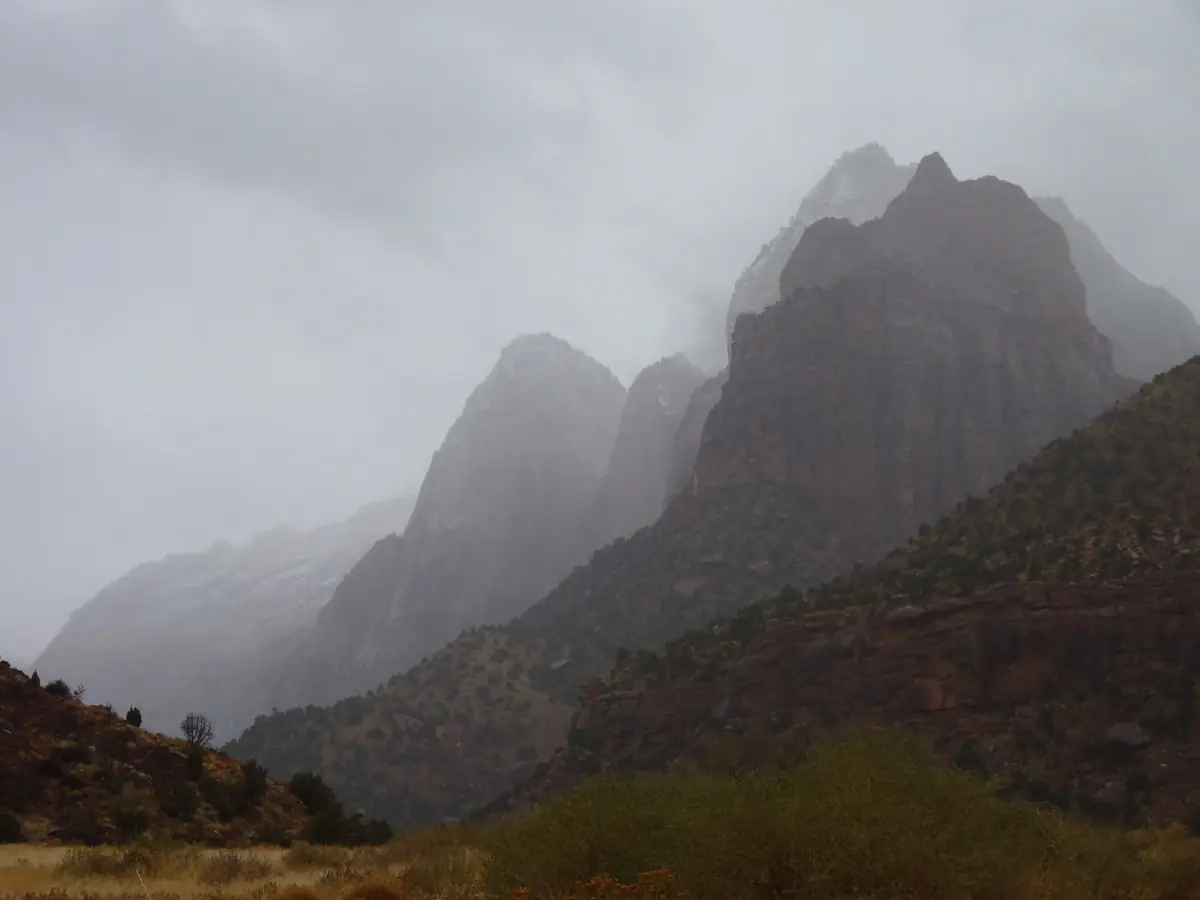 Rain clouds drifting around gray sandstone peaks in winter, Zion National Park.